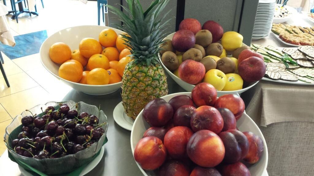 A table with various fruits including oranges, pineapple, apples, kiwis, and plums.
