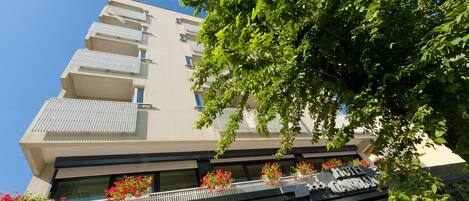A multi-story hotel with balconies, flower boxes, and a sign indicating parking availability.