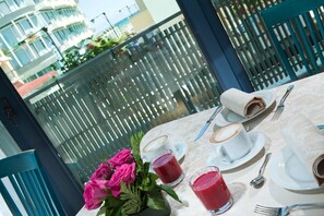 A table set for two with a view of a balcony and buildings.