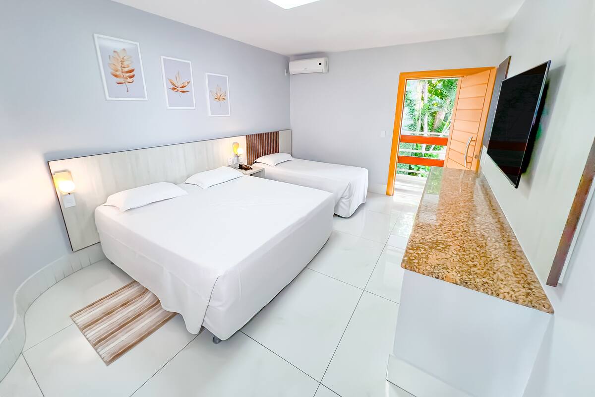 A hotel room with two beds, a TV, and artwork on the wall.