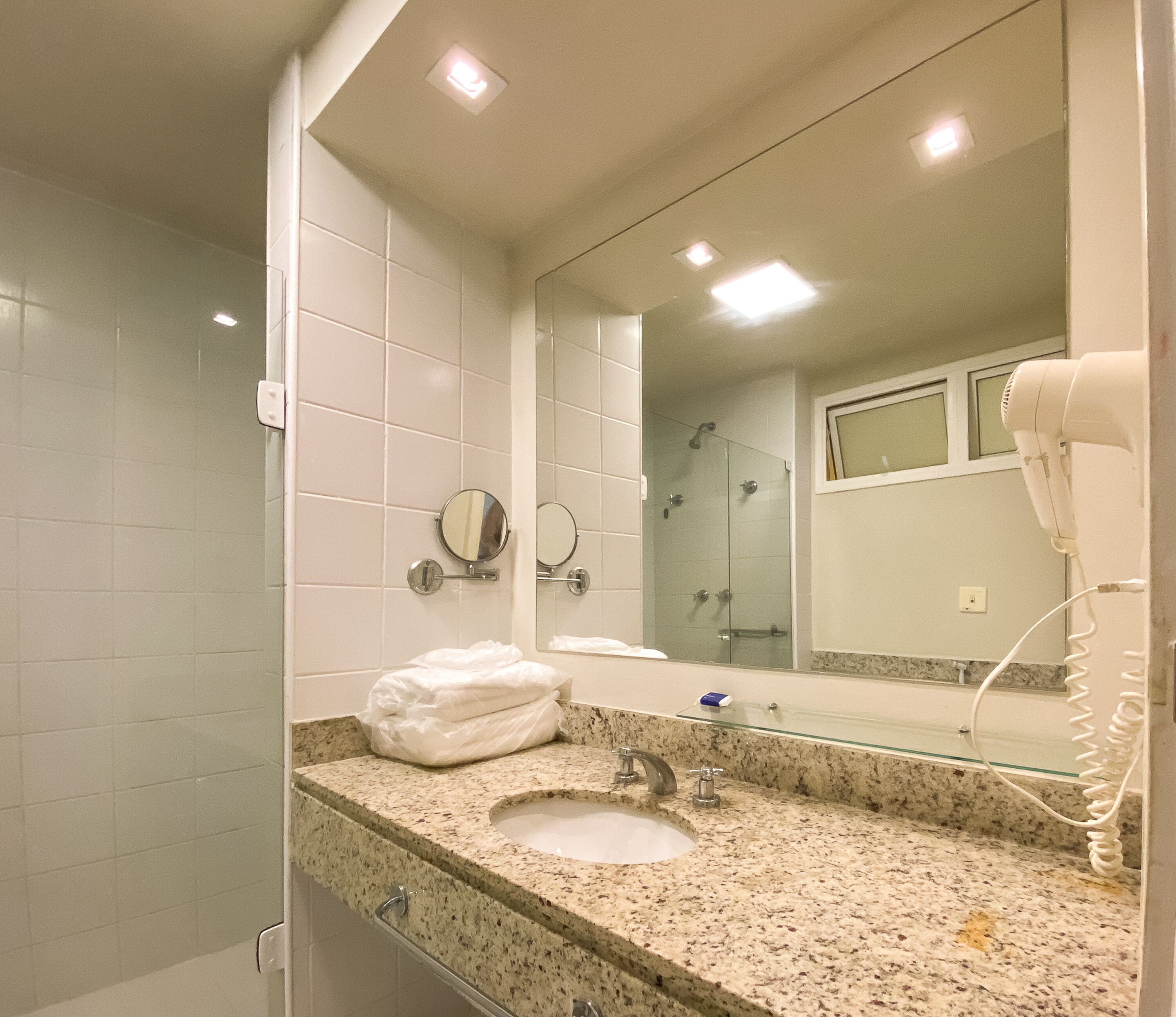 A bathroom with a sink, mirror, towel rack, and hair dryer.