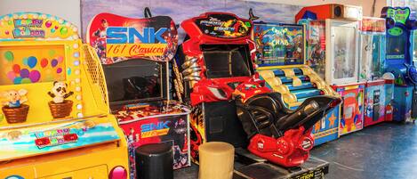 Una fila de máquinas de arcade en una habitación con suelo de concreto y una pared con grafitis.