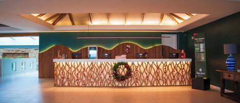Un mostrador de recepción con un fondo decorativo, una pantalla digital y un letrero para un restaurante.