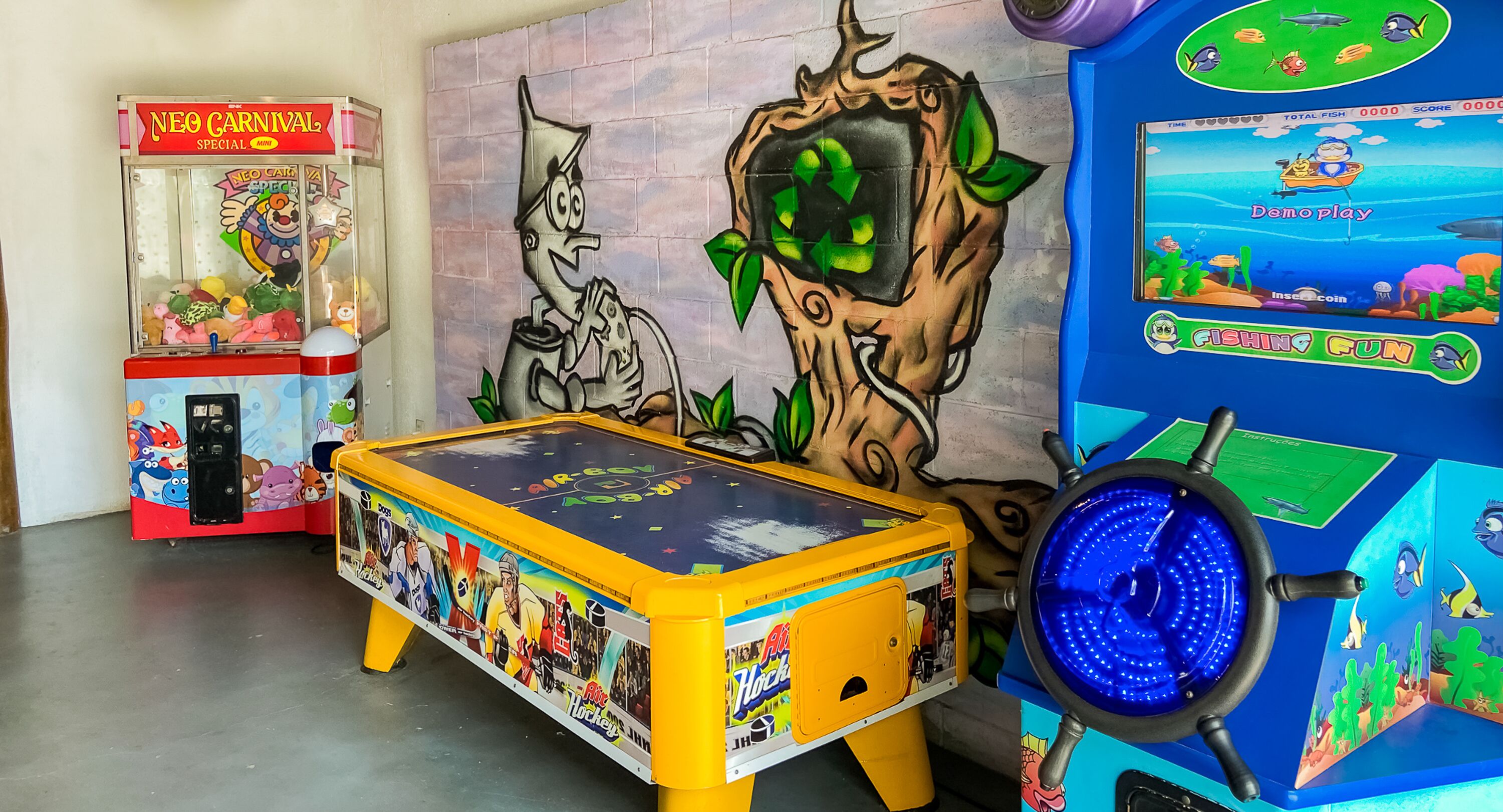 A room with a pool table, a claw machine, and a video game console.