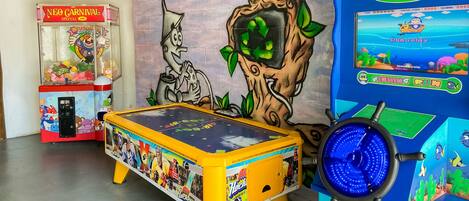 A room with a pool table, a claw machine, and a video game console.