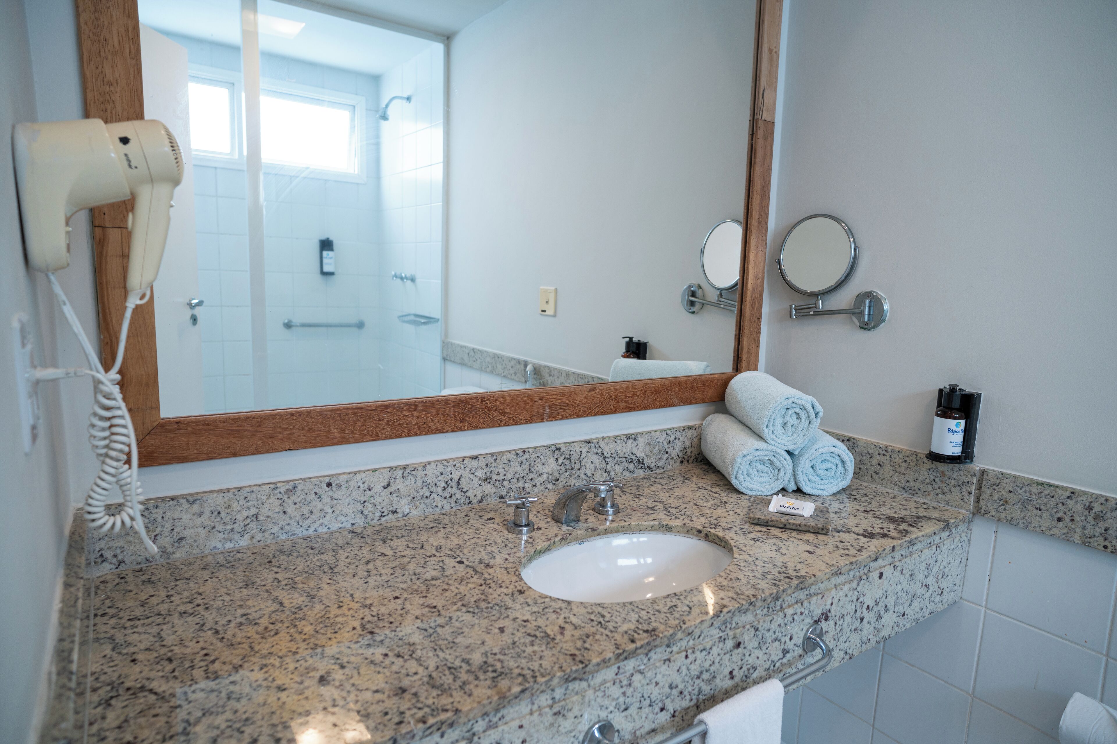 A bathroom with a granite countertop, a sink, a hairdryer, a mirror, and towels.