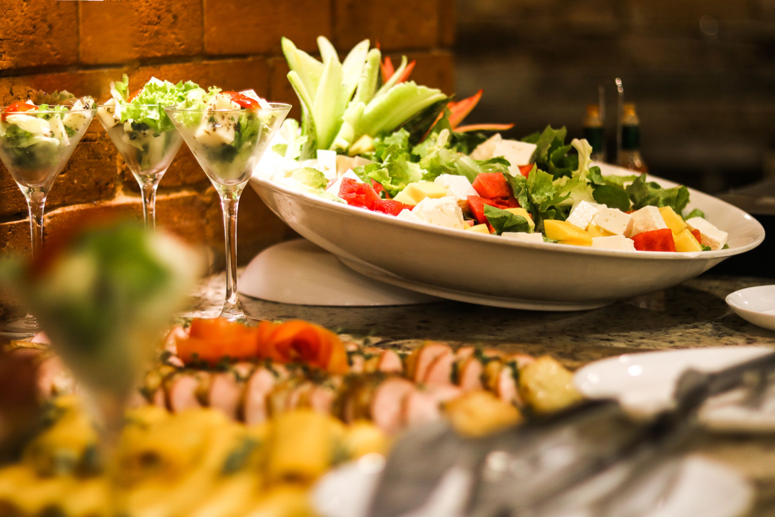 Un buffet proposant divers plats, notamment un grand saladier, une assiette de charcuteries et un verre de boisson.