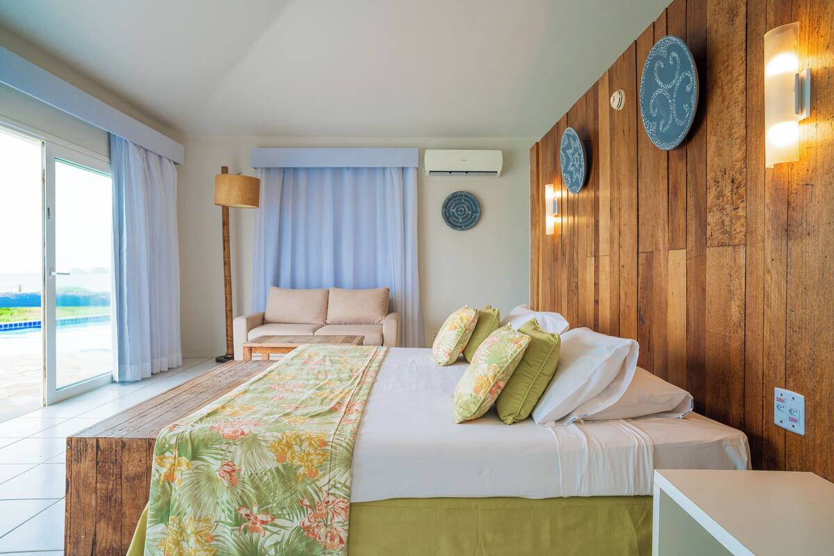 A hotel room with a bed, a sofa, a large window, and a view of the outdoors.