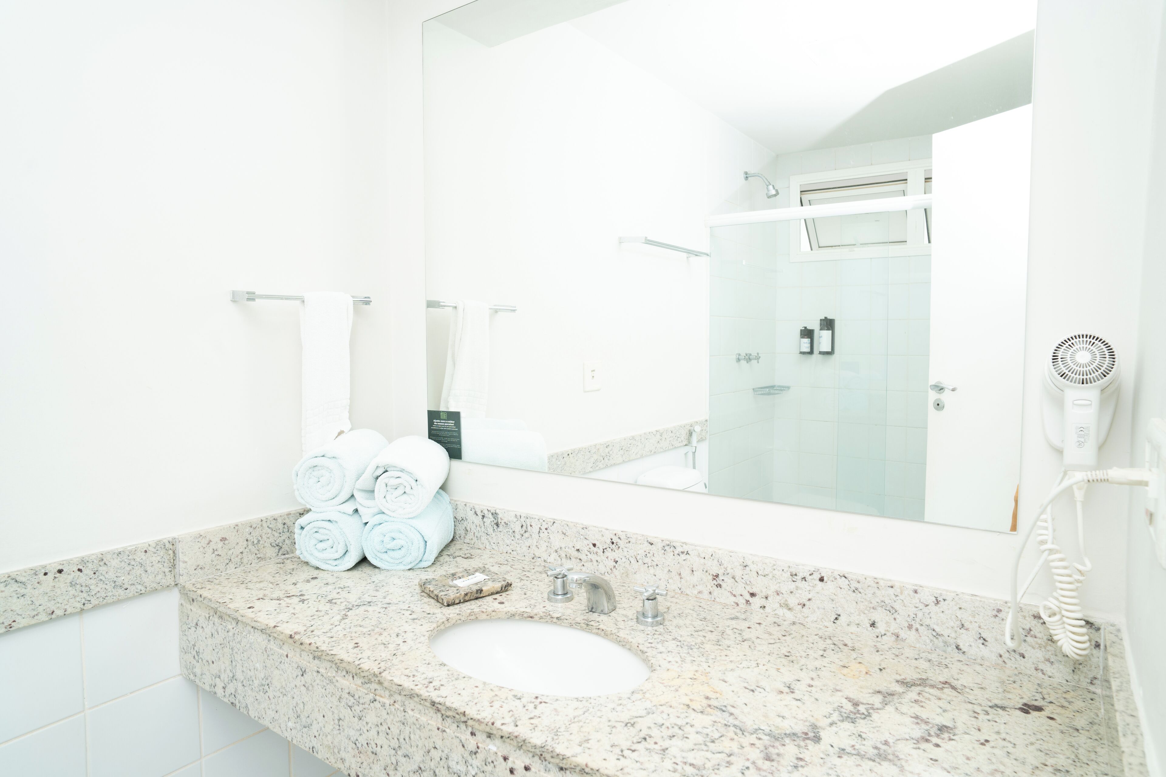 A bathroom with a granite countertop, a sink, a mirror, and a towel rack with towels.