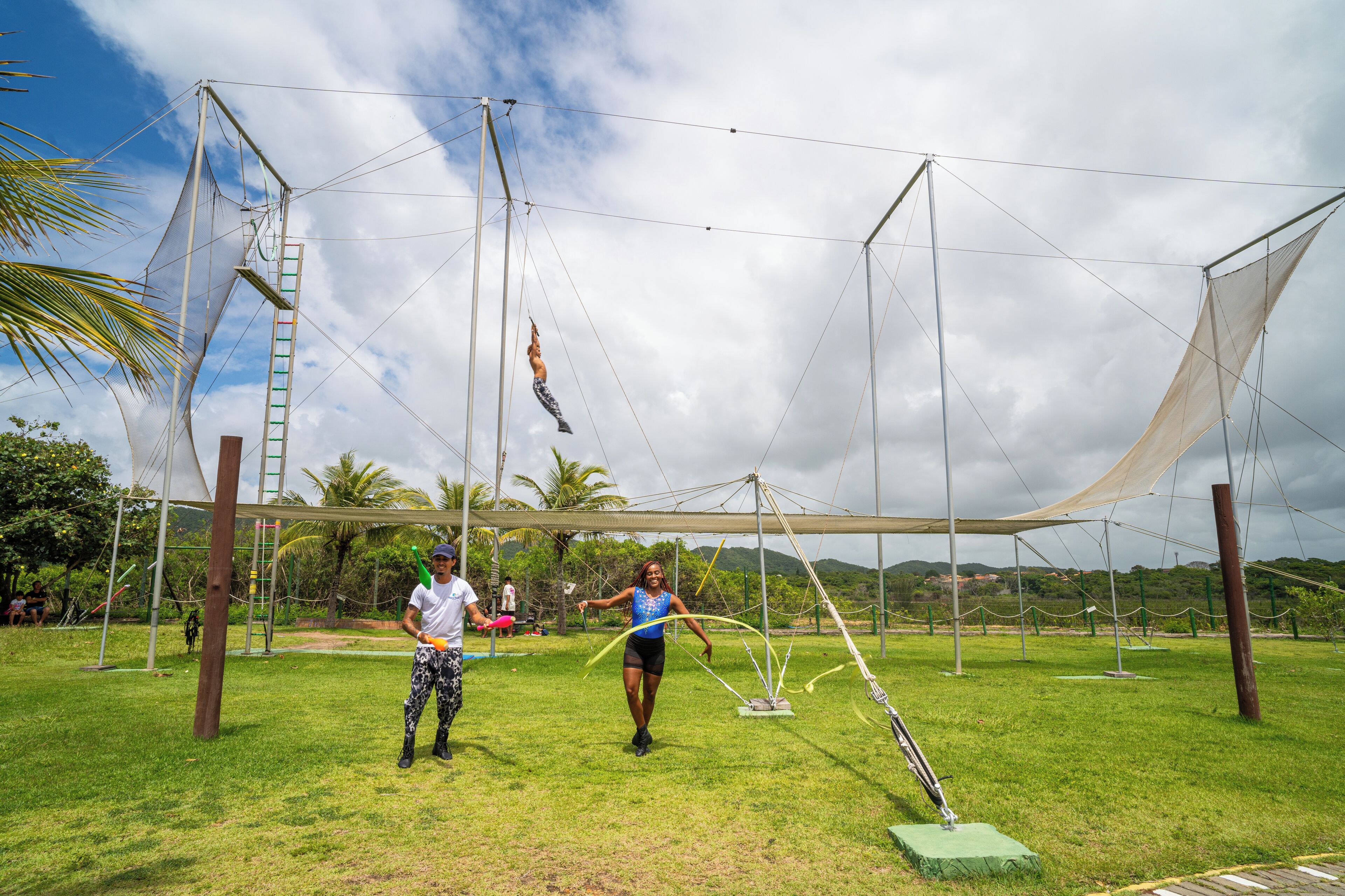A tented outdoor area with a grassy field, a climbing ladder, and a rope swing.