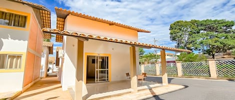 Una casa de dos pisos con un porche cubierto, una puerta visible y una ventana.
