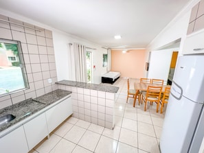 Uma cozinha compacta com área de refeições, uma cama e um frigorífico.