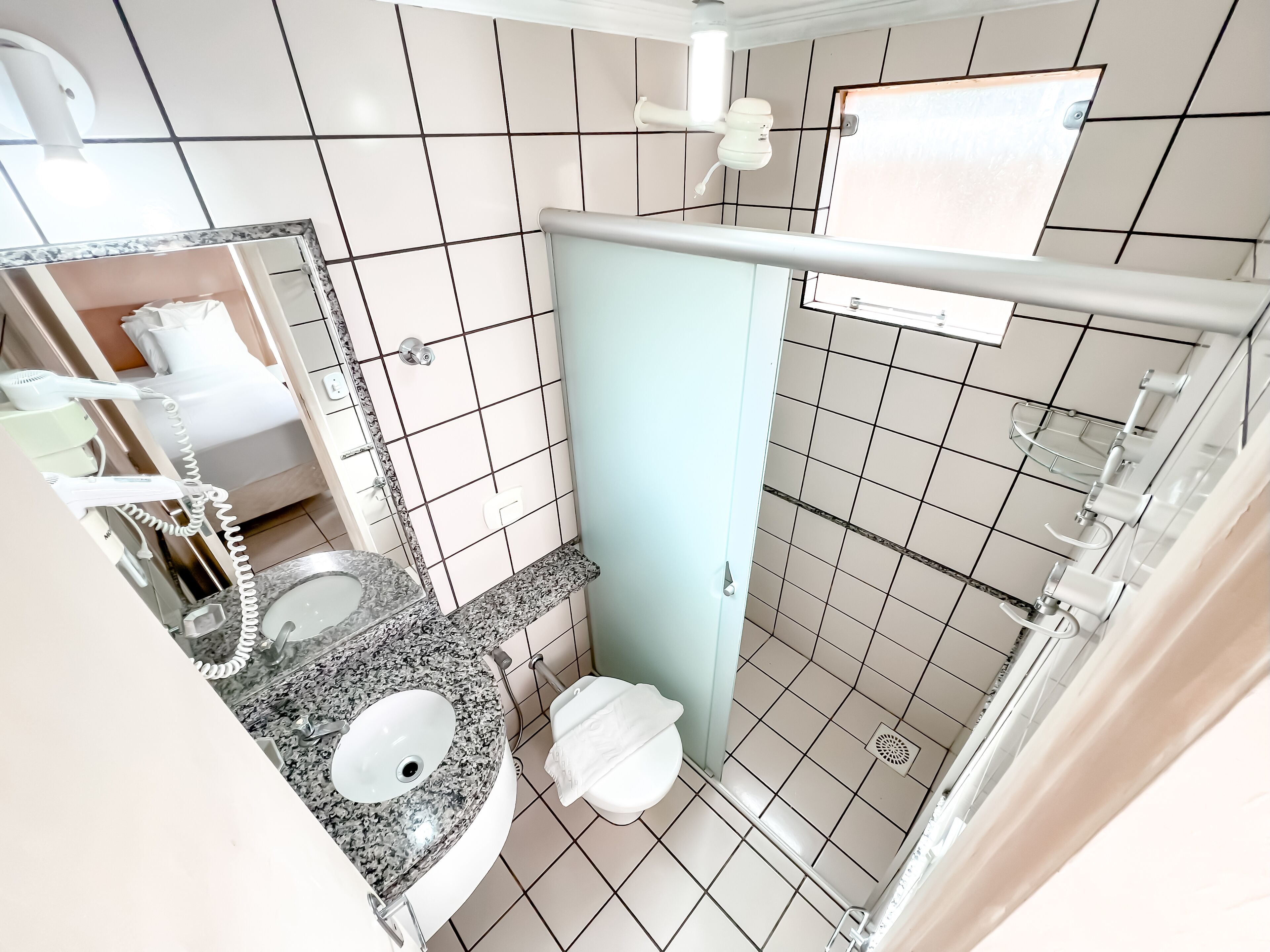 A bathroom with a granite sink, white toilet, and a shower area.