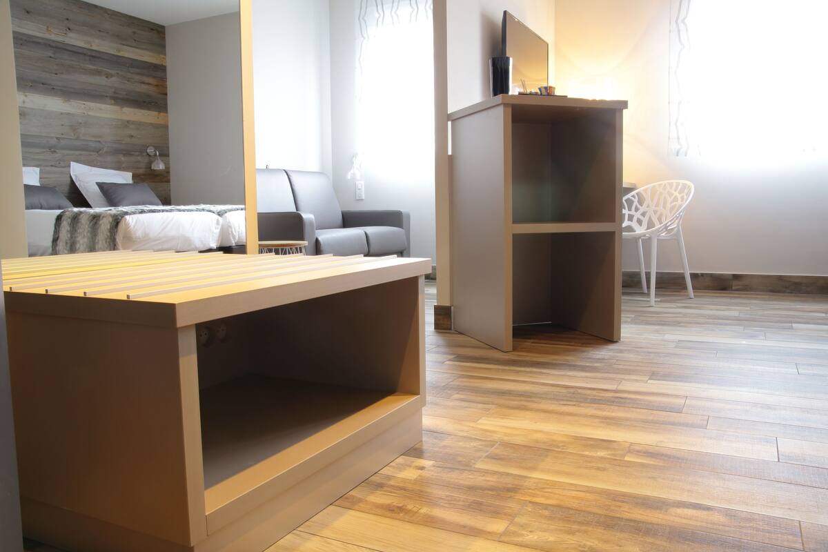 Une chambre moderne avec un lit en bois, un canapé gris et une chaise blanche.