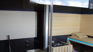 Un baño moderno con mampara de vidrio, zona de ducha y tocador de madera con una tira de luz azul.