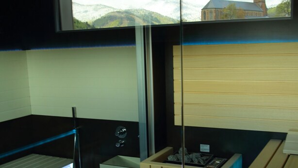 Habitación compacta con literas, una kitchenette pequeña y una ventana que ofrece vistas a una iglesia y colinas.