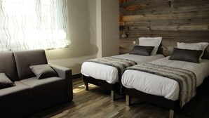 Una habitación con dos camas, un sofá y un panel de madera.