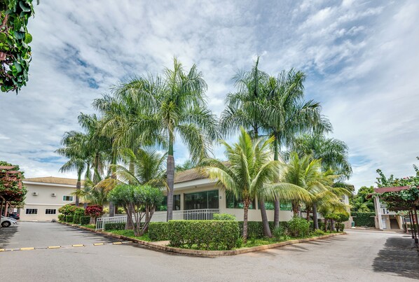 A building with a parking lot, surrounded by palm trees and greenery.