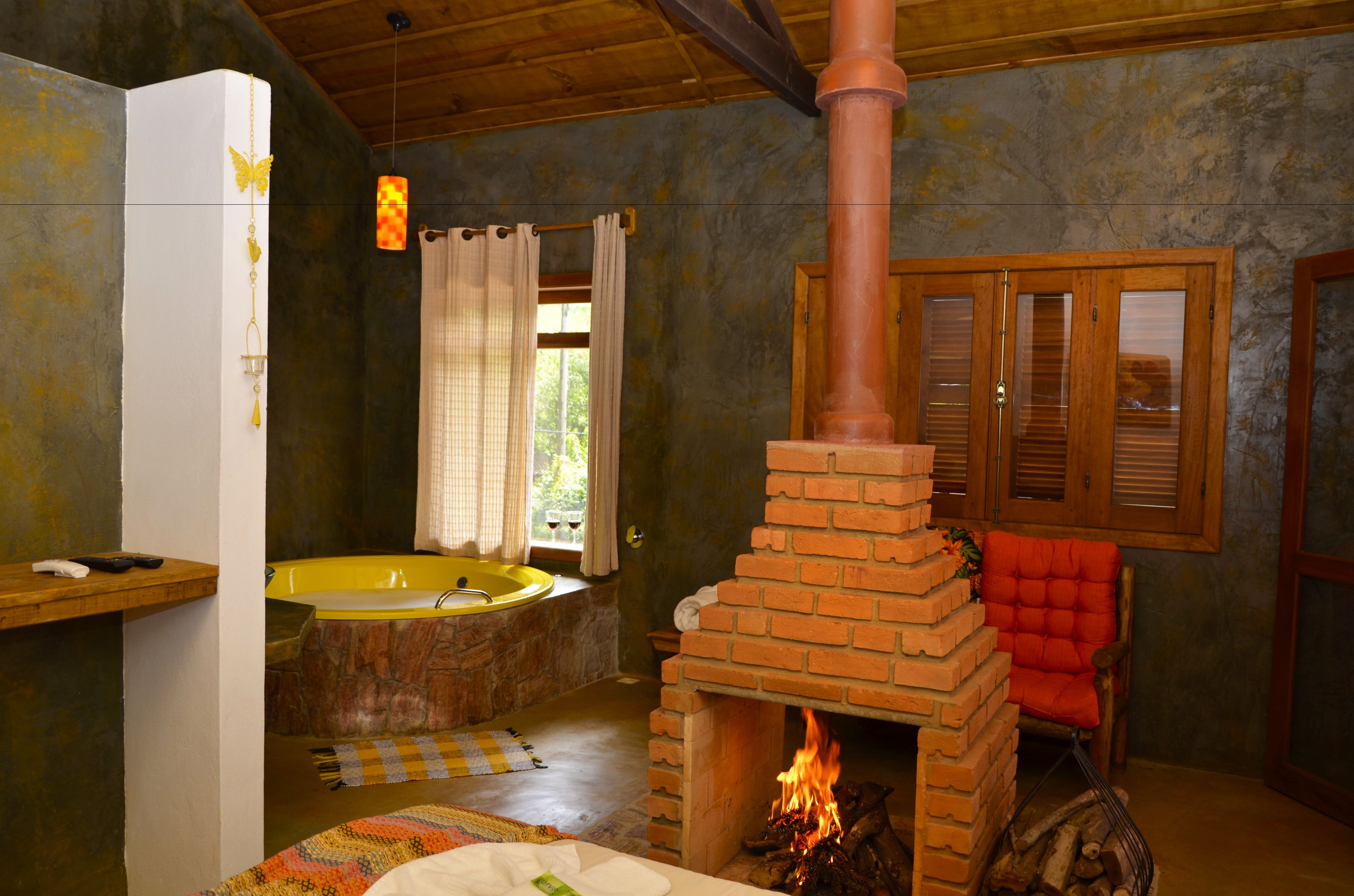 A rustic bathroom with a brick fireplace, a bathtub, and a wooden chair.
