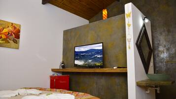 Un dormitorio con una cama, un televisor montado en una pared texturizada, un armario rojo y un lavamanos verde.