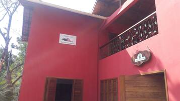 Un edificio rojo con un letrero que dice 'Noz de Macadamia', una puerta de madera y un balcón con barandas de metal.