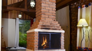 Ein Kamin aus Ziegelsteinen mit Feuer, Holzbalken und eine Steinwand.