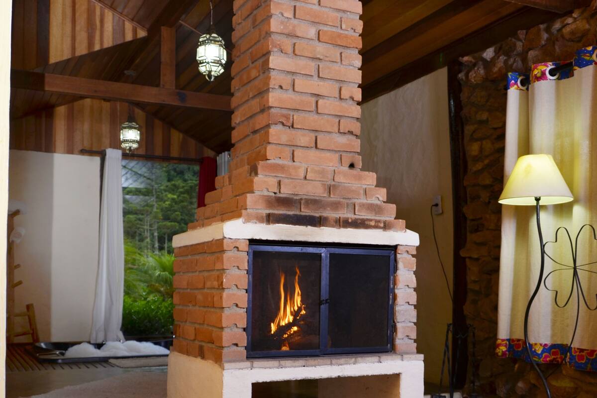 Una llar de foc de totxins amb foc, bigues de fusta i una paret de pedra.