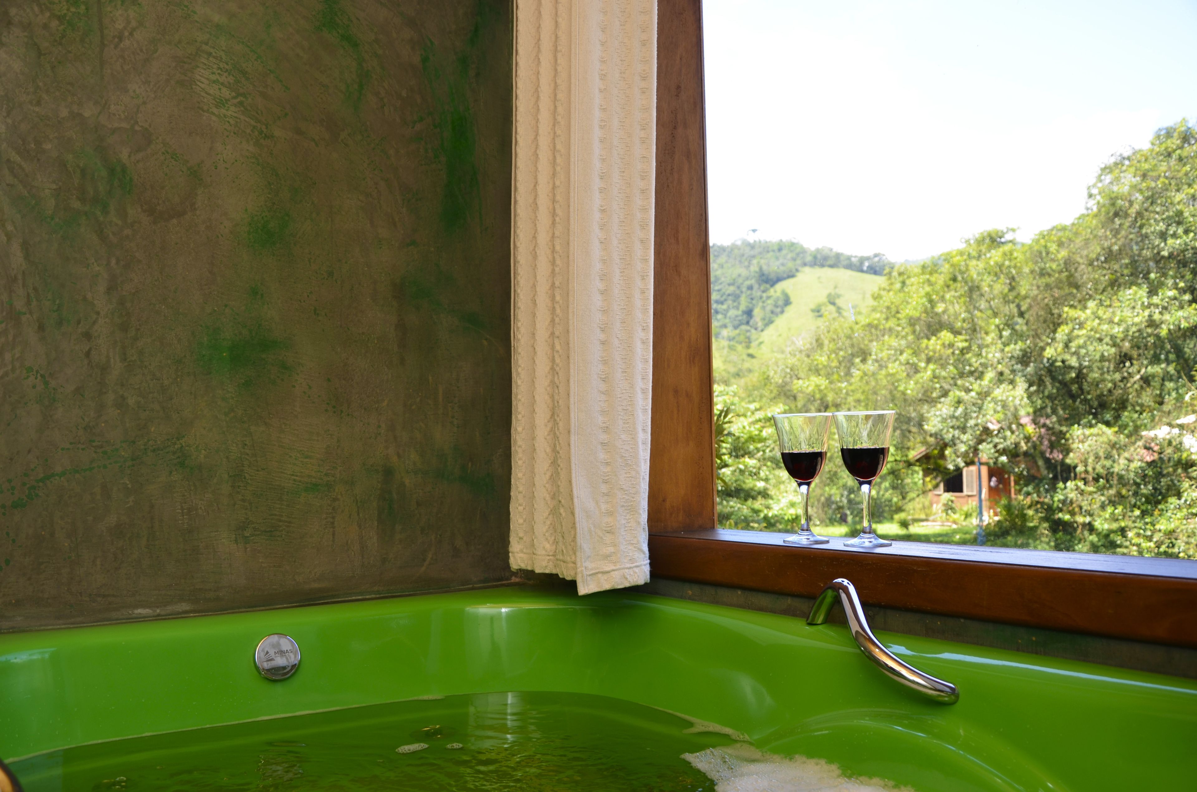 A green bathtub with a window view of a green landscape.