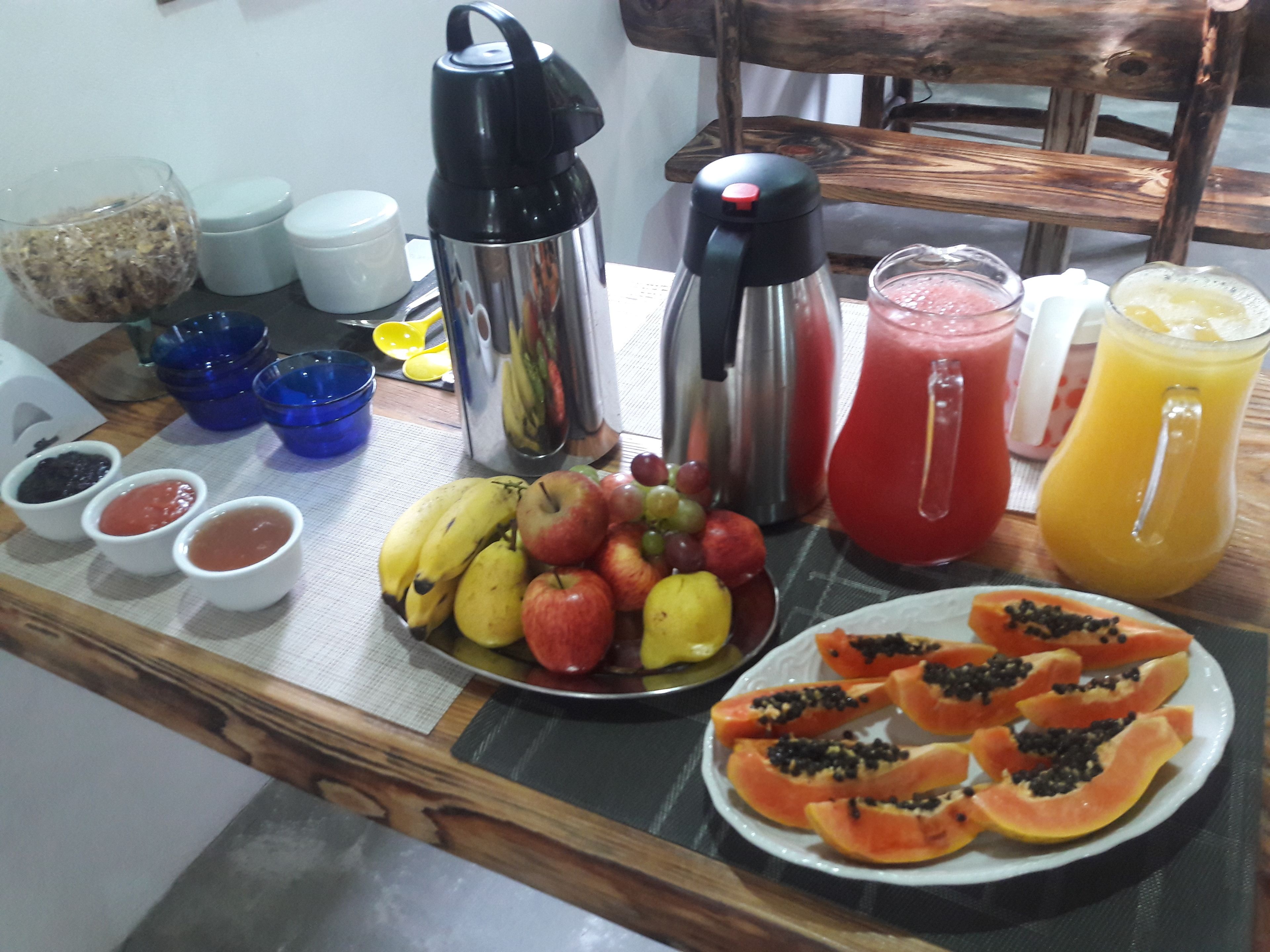 Una mesa de desayuno con frutas, salsas y bebidas.