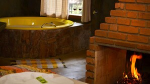 Ein Badezimmer mit einer gelben Badewanne, einer Steinwand, einem Kamin aus Ziegeln und einem Schachbrettteppich.