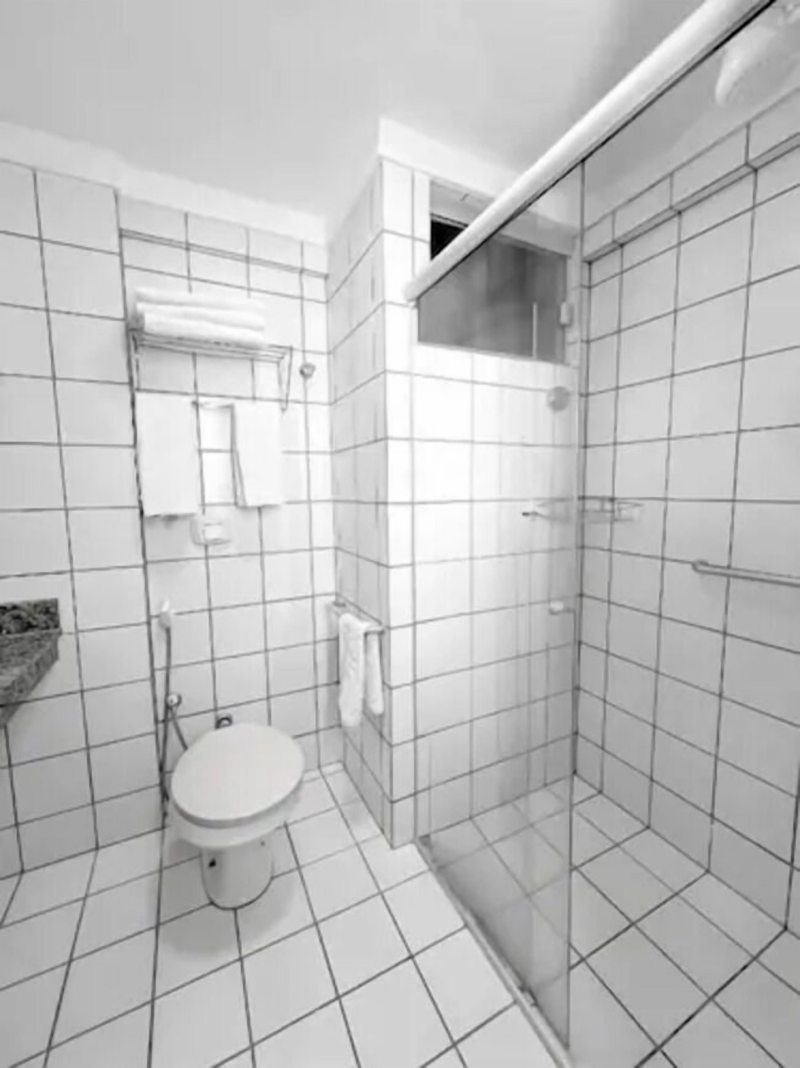 A modern bathroom with a toilet, a shower enclosure, and a tiled floor.
