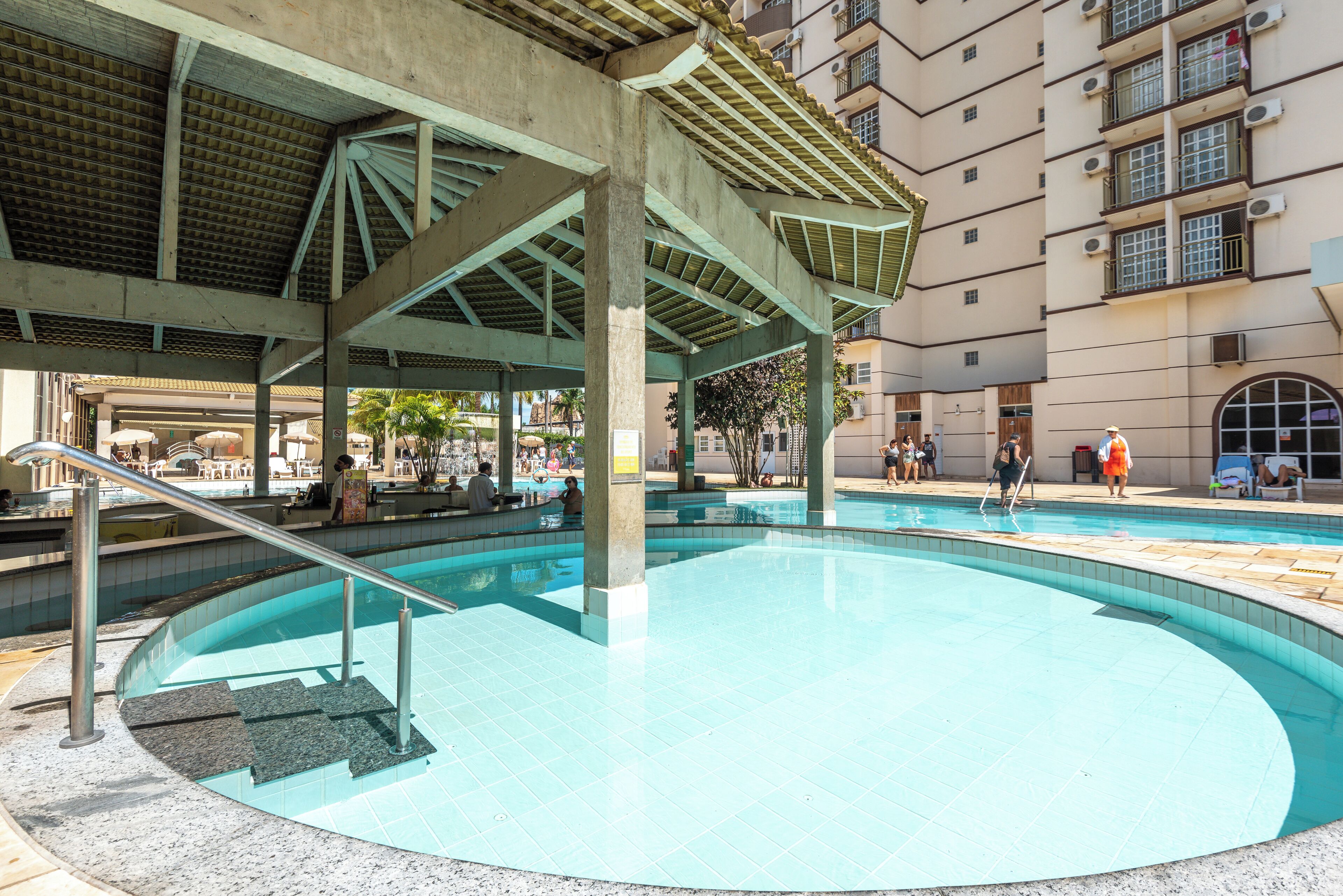 A swimming pool with a covered area and a building in the background.