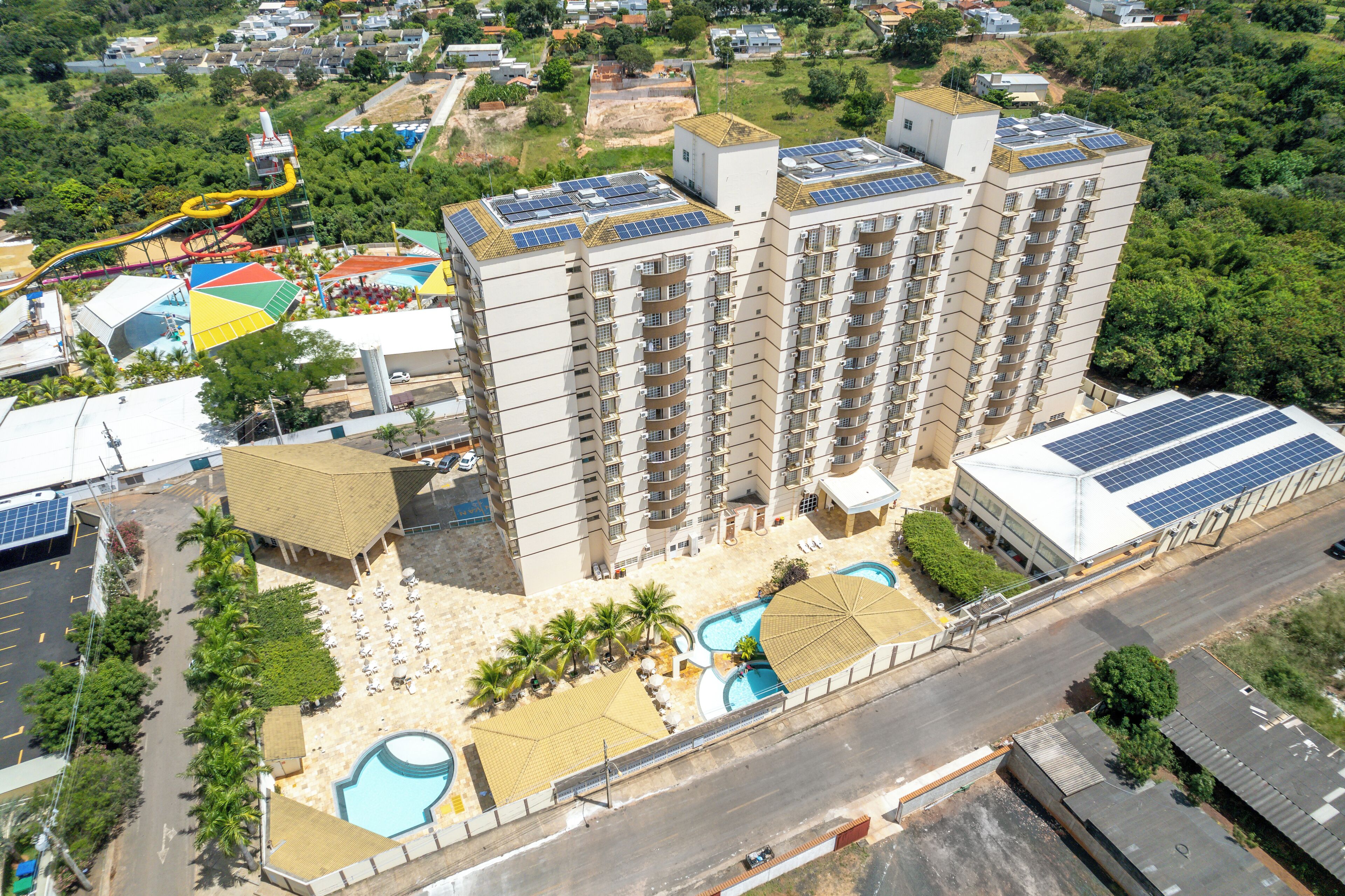 A high-rise hotel with multiple balconies, a swimming pool, and solar panels on the roof.