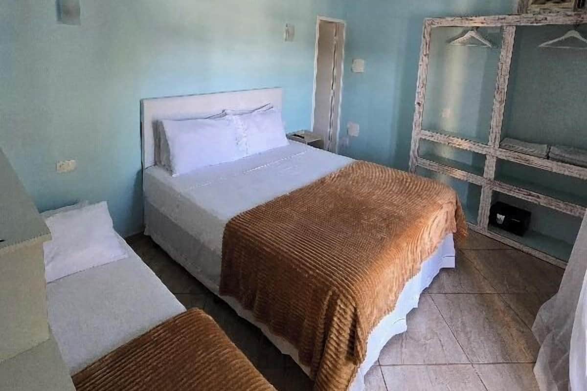 A bedroom with a bed, a bedside table, a wardrobe, and a mirror.