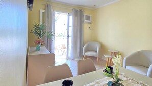 Un comedor con una mesa dispuesta para dos, una planta en maceta y vistas al exterior.