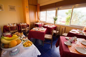 A dining area with tables set for breakfast, featuring fruits and beverages.