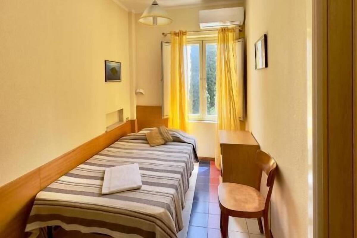 A hotel room with a bed, a desk, and a chair.
