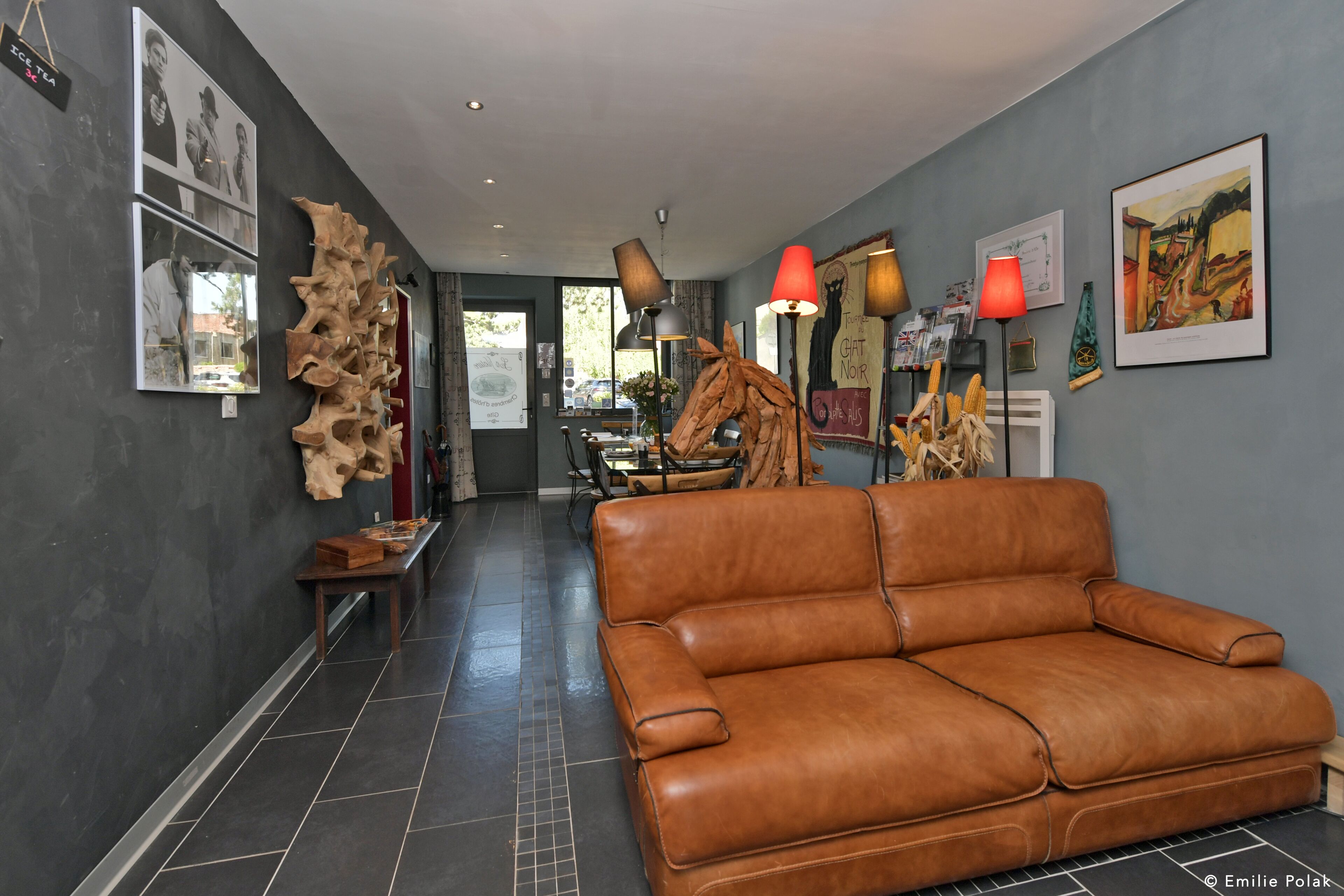 A modern interior with a leather sofa, artwork, and a unique wooden sculpture.