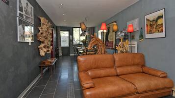 A modern interior with a leather sofa, artwork, and a unique wooden sculpture.