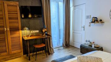 Habitación de hotel con un escritorio de madera, un globo terráqueo, una lámpara, una silla, una cama, una maleta y una estantería con objetos.