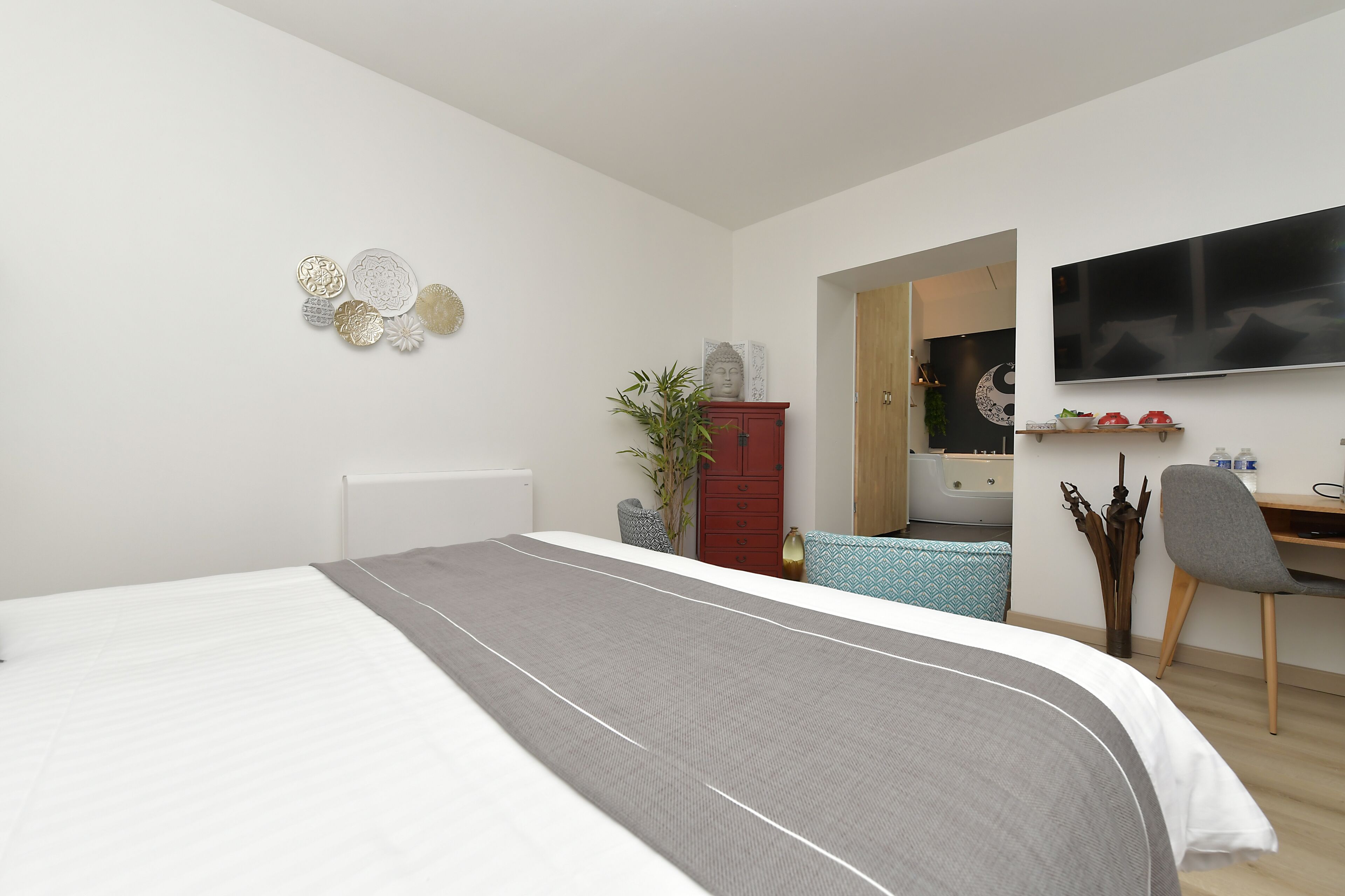 Un dormitorio moderno con cama, televisión, escritorio y armario.