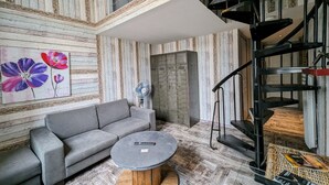 Un salon moderne avec un canapé gris, une table basse ronde et un tableau représentant des fleurs accroché au mur.