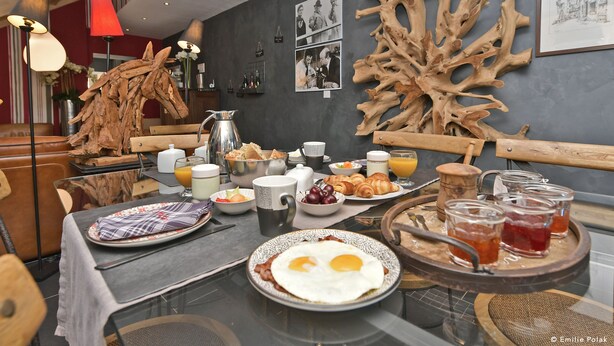 Une table mise pour le petit-déjeuner, avec des places pour deux personnes, comprenant des œufs, des croissants et des boissons.
