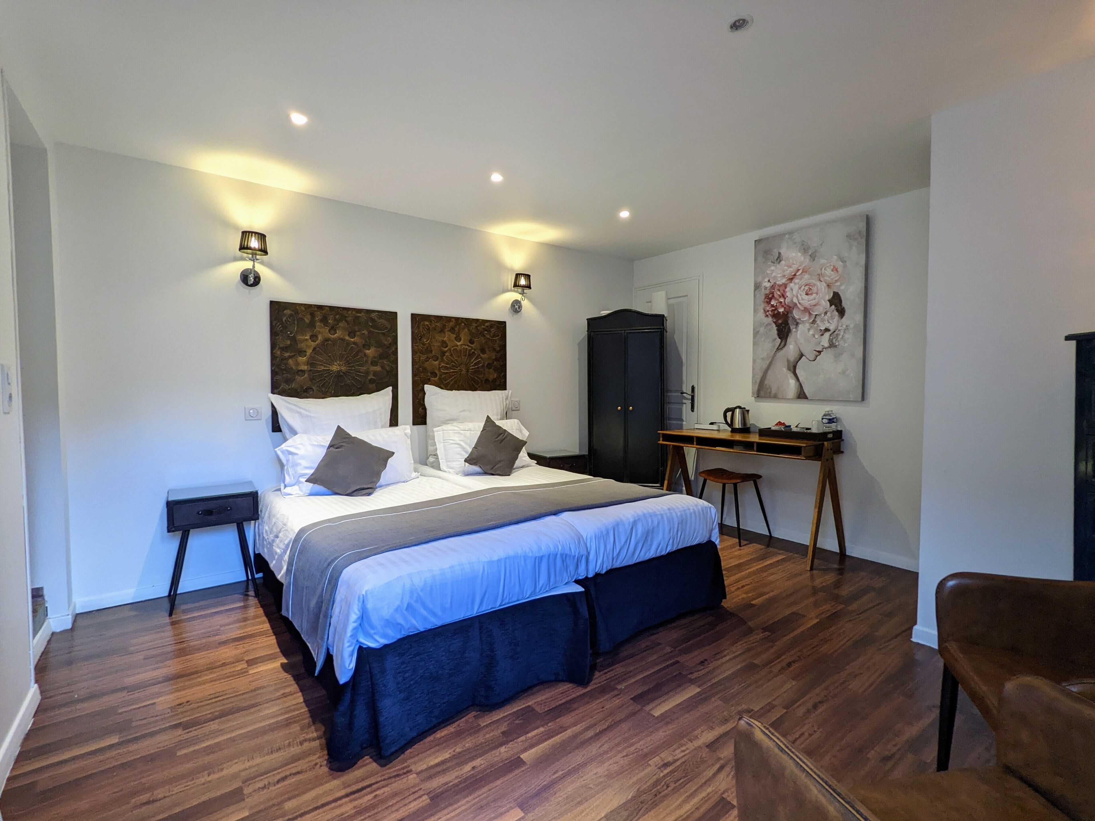 A modern bedroom with a large bed, a desk, and a cabinet.