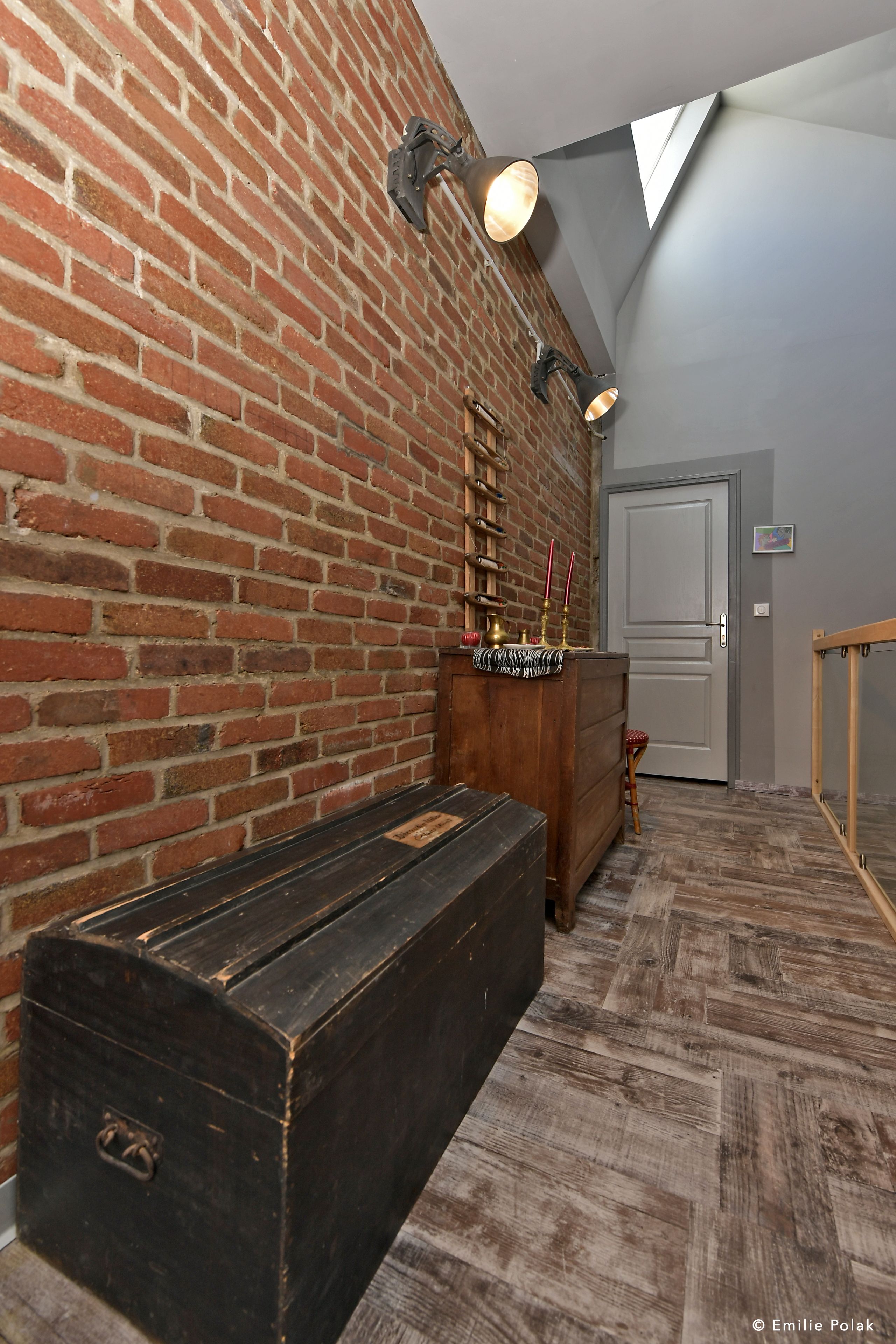 Una habitación con pared de ladrillo, un banco de madera, un aparador y una puerta.