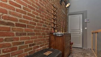 Una habitación con pared de ladrillo, un banco de madera, un aparador y una puerta.