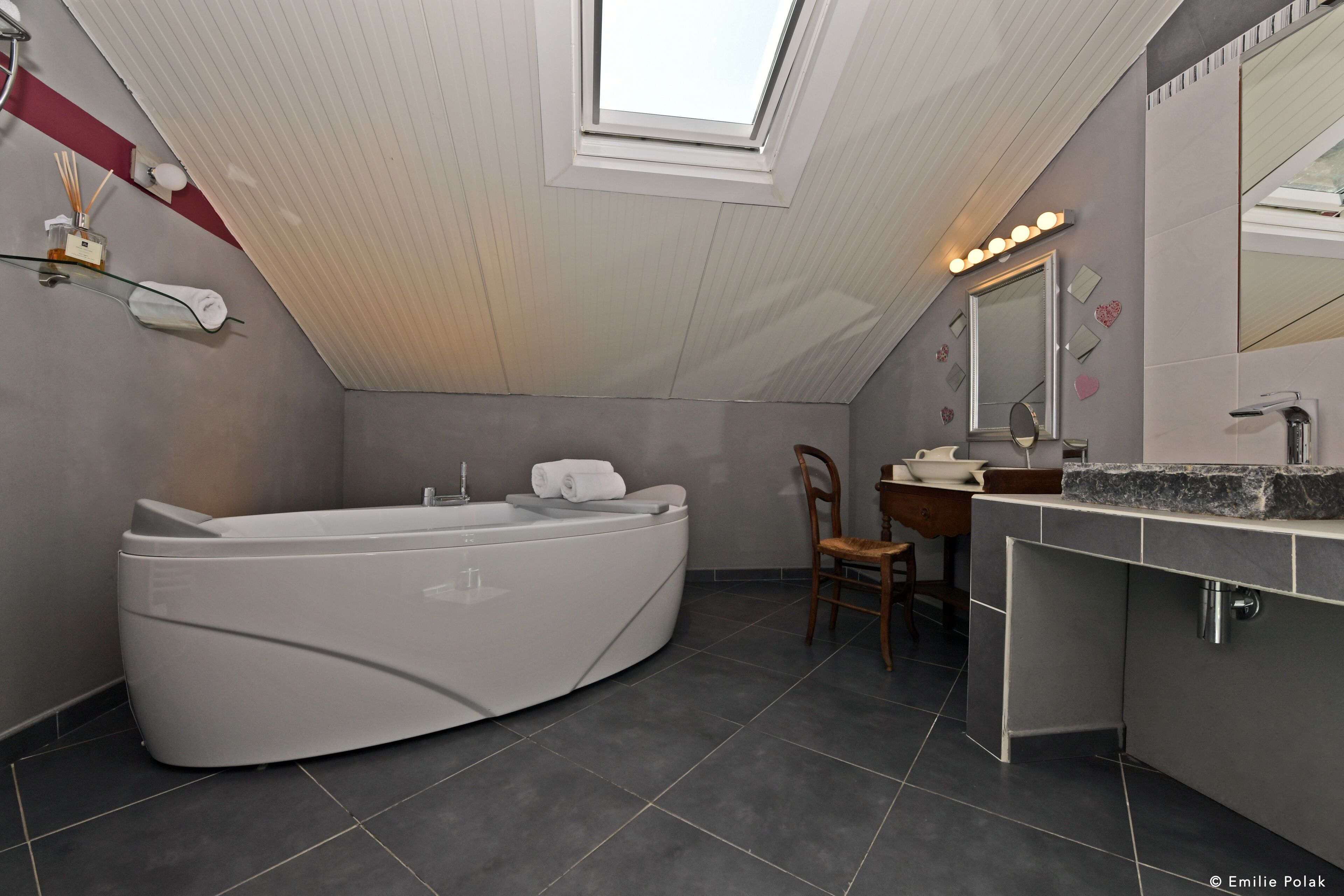Une salle de bain moderne avec une baignoire sur pieds, un meuble-lavabo avec un miroir et une lucarne.
