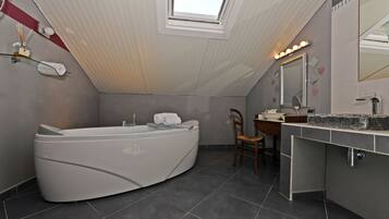 Une salle de bain moderne avec une baignoire sur pieds, un meuble-lavabo avec un miroir et une lucarne.