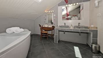 A modern bathroom with a skylight, a bathtub, a vanity with a mirror, and a chair.