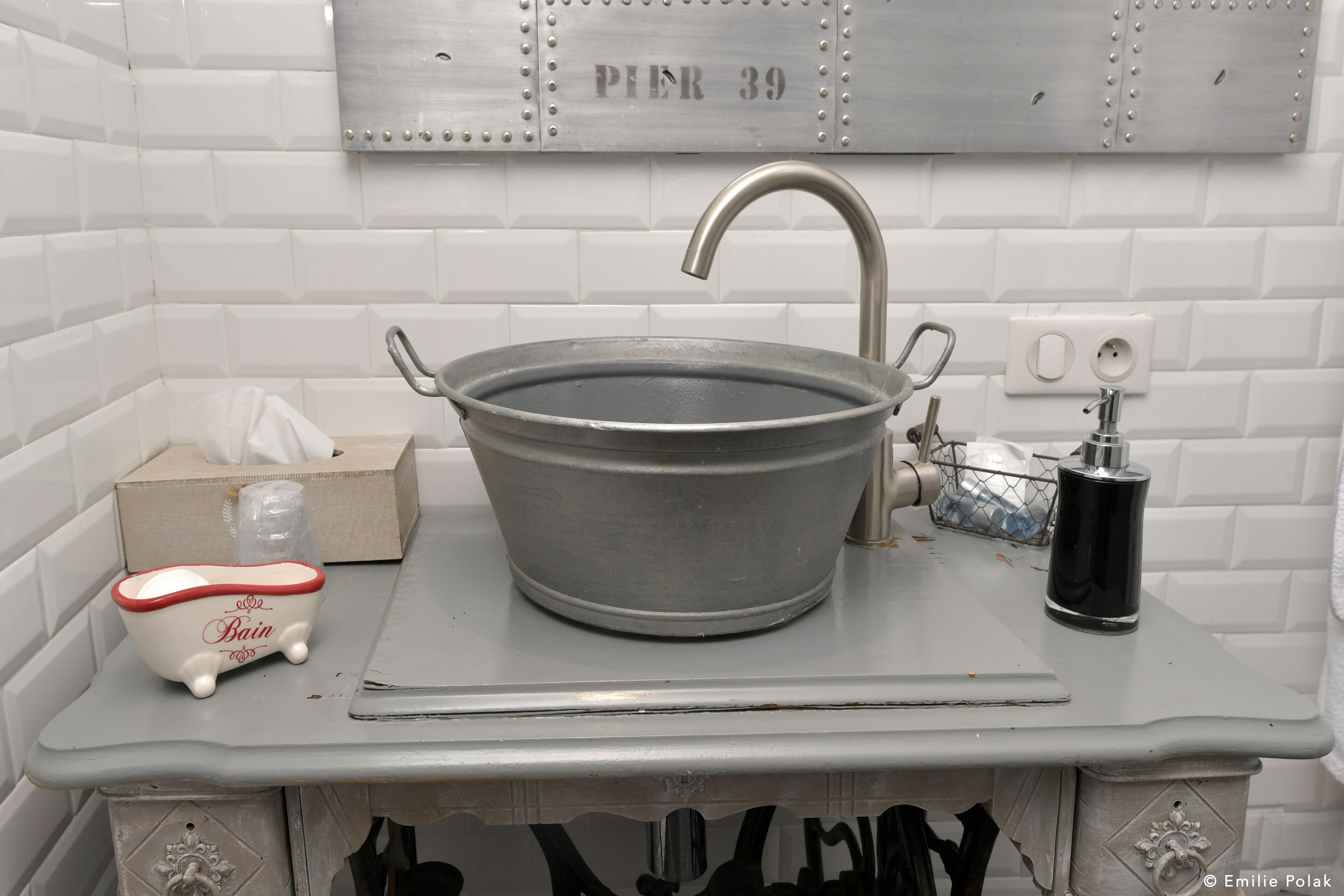 A bathroom with a large metal basin sink, a small decorative bathtub, and a towel rack.